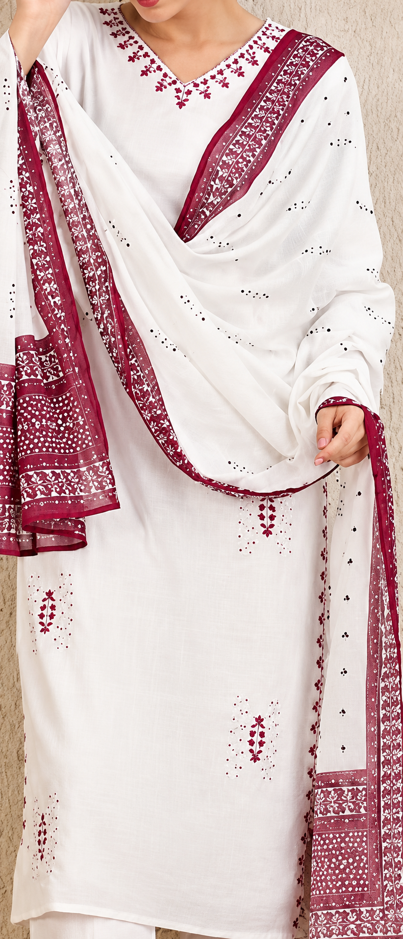White cotton kurta set with deep red border and matching dupatta featuring embroidered details and eyelet embroidery, shown on a model.